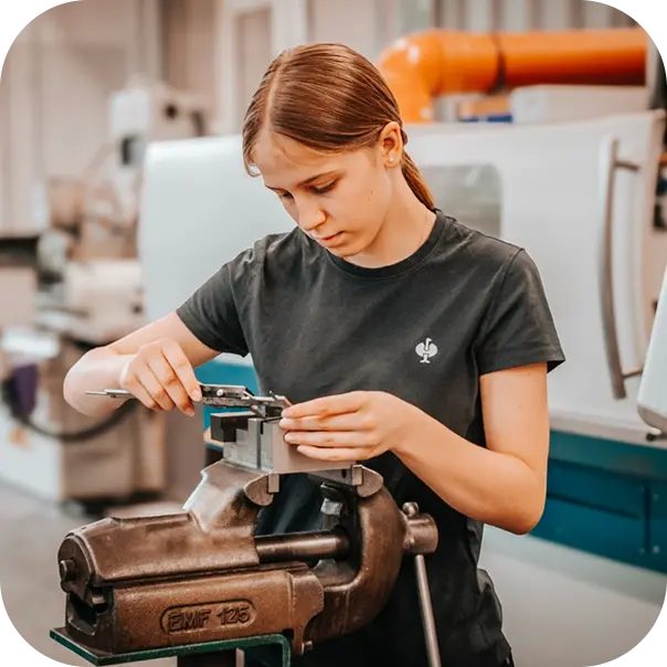 Mitarbeiterin bei der manuellen Bearbeitung eines kleinen Metallteils