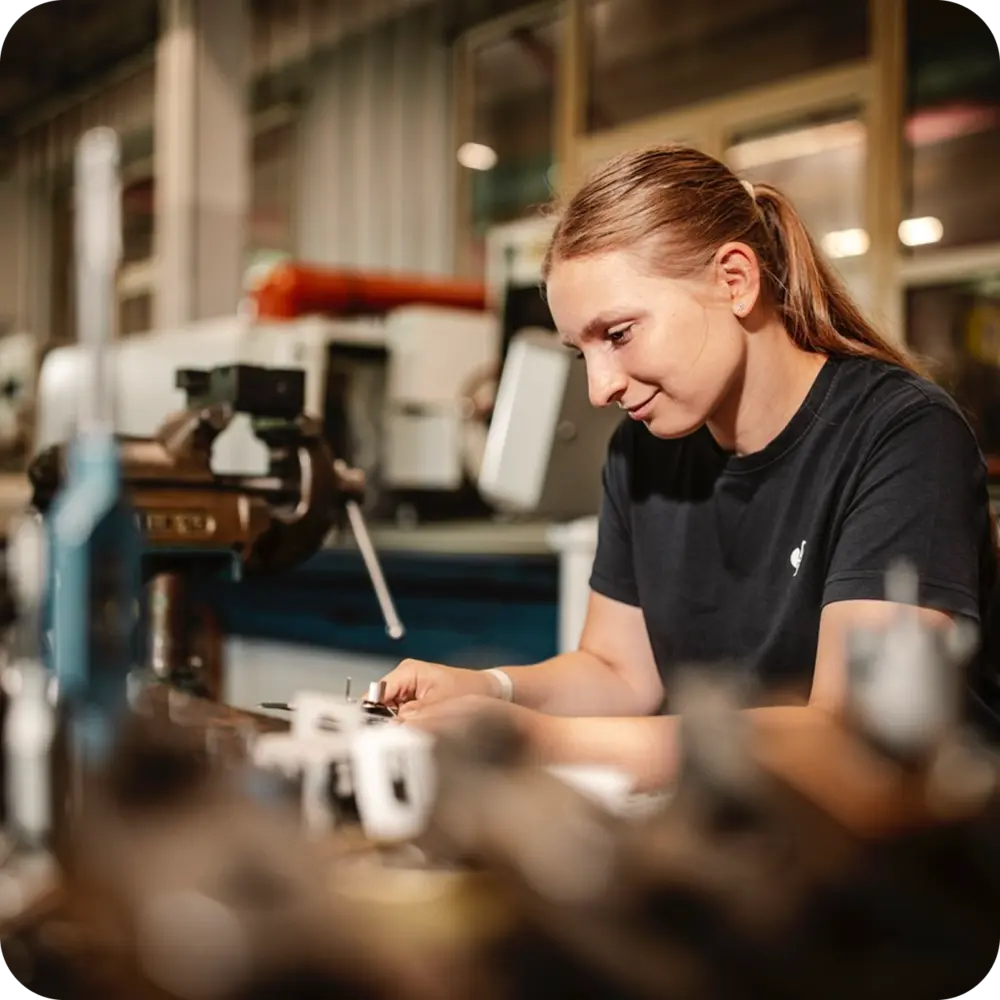Mitarbeiterin bei der manuellen Bearbeitung eines kleinen Metallbauteils