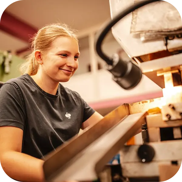 Mitarbeiterin bei der Bearbeitung eines Metallteils an einer Maschine