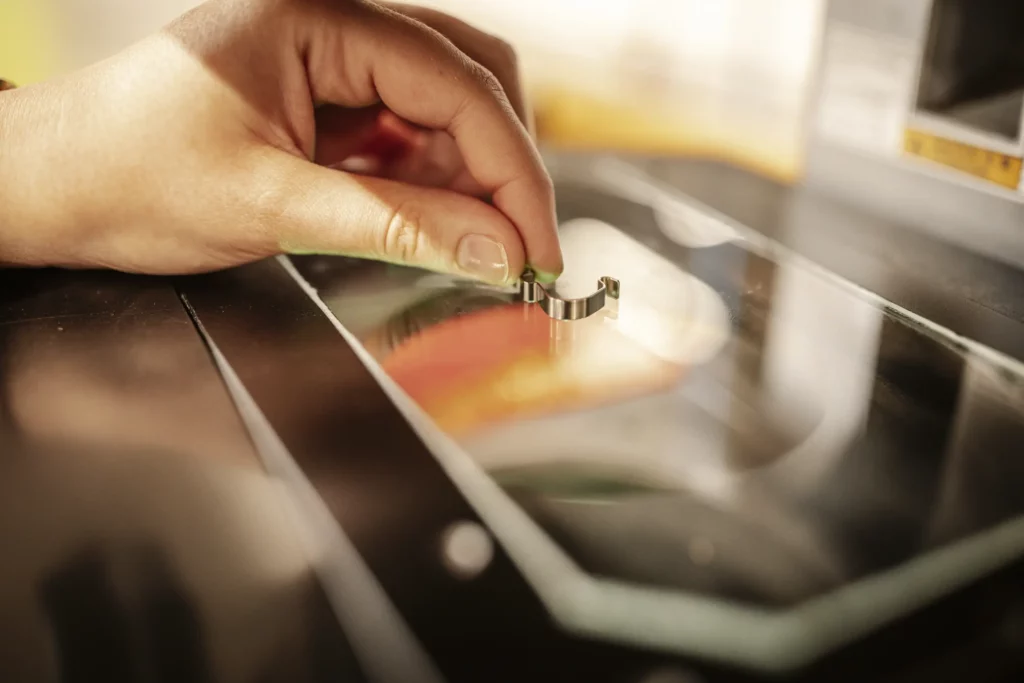 Hand bei der Vermessung eines kleinen Metallbauteils