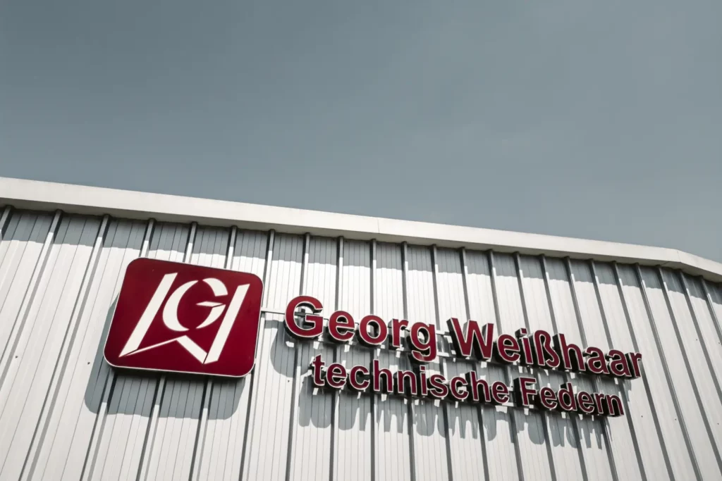 Firmenlogo der Georg Weisshaar techn. Federn GmbH an einem Gebäude